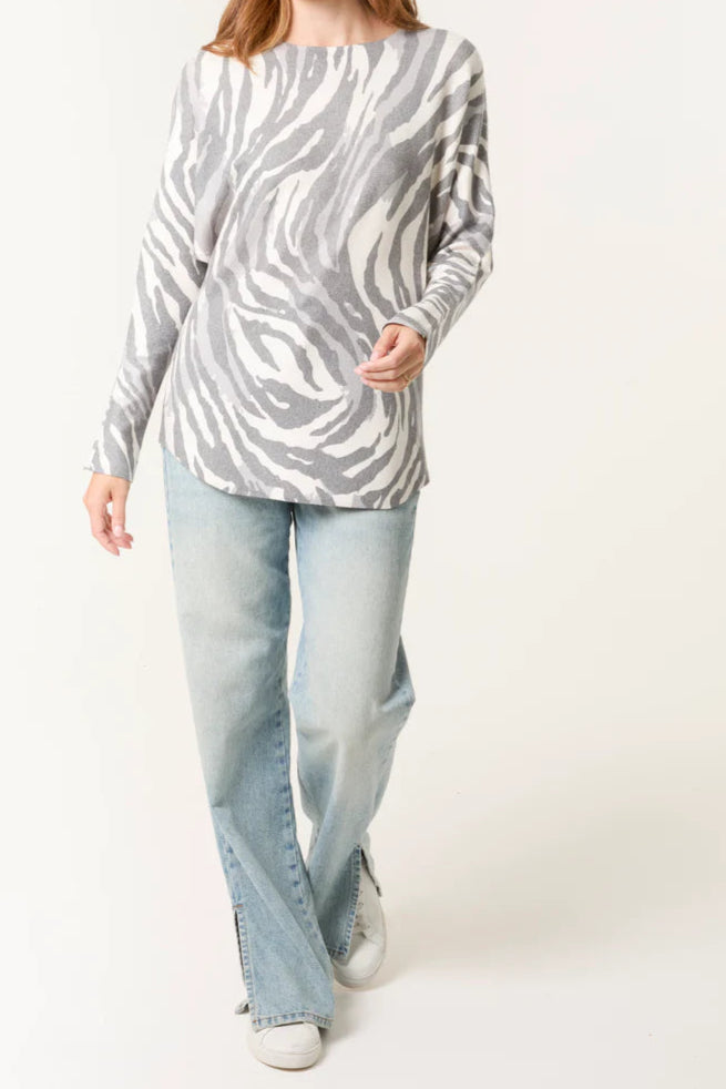 Woman wearing a zebra print sweater and light blue jeans on a white background