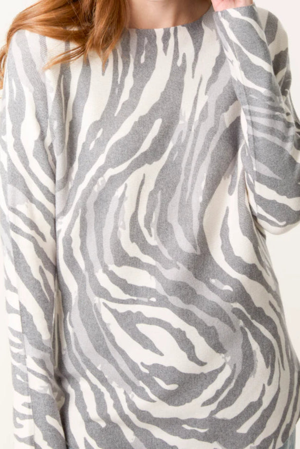 Woman wearing a gray and white zebra pattern sweater on a white background