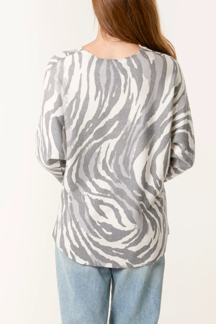 Person wearing a gray and white zebra patterned top on a white background